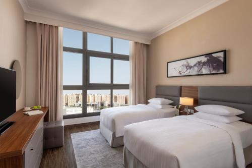a hotel room with two beds and a large window at Marriott Executive Apartments Doha, Le Mirage City Walk in Doha