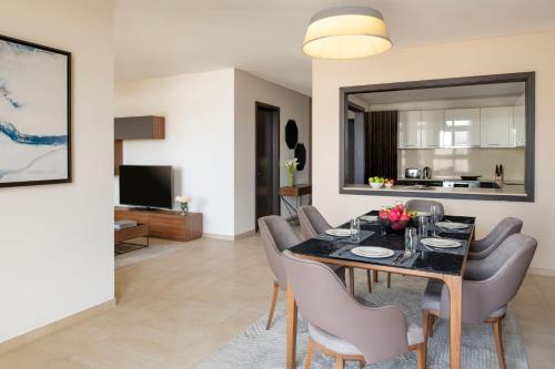 a living room with a dining room table and chairs at Marriott Executive Apartments Doha, Le Mirage City Walk in Doha
