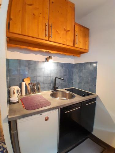 une petite cuisine avec un évier et une cuisinière dans l'établissement Y'Hôtes - Studio Evasion près des pistes, à Saint-Jeoire