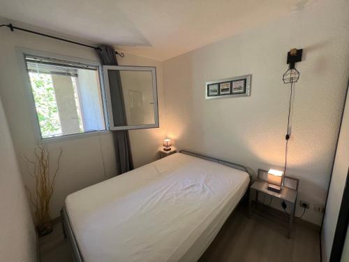 mała sypialnia z łóżkiem i oknem w obiekcie ANTINEA Joli T2 cabine piscine proche plage Richelieu cap d'Agde w Cap d'Agde