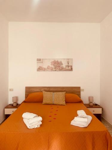 a bedroom with an orange bed with towels on it at Appartamenti Il Sole Parghelia in Parghelia