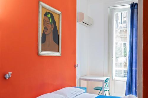 a bedroom with an orange wall with a painting of a woman at A Casa di Amici in Palermo