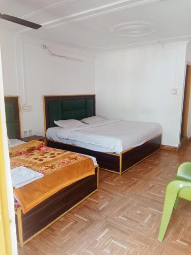 a bedroom with two beds and a green chair at Sandeep homestay in Dharamshala