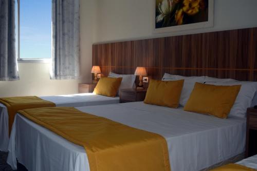 um quarto de hotel com duas camas com almofadas amarelas em Hotel Diplomata Copacabana no Rio de Janeiro