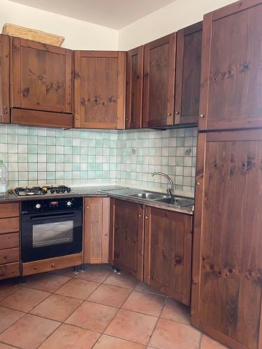 a kitchen with wooden cabinets and a sink at La Casa Sul Lago in Bortigiadas