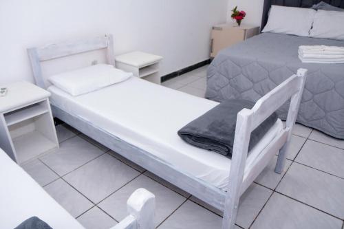 a bedroom with two beds and a small table at Vila Iriri - Pousada e Camping in Anchieta