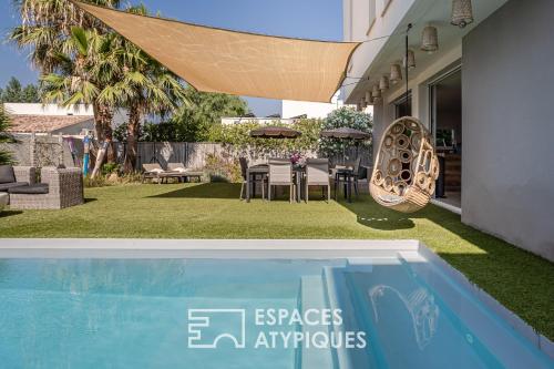 a swimming pool in a backyard with a table and chairs at Villa proche plage mer, piscine grand terrain Capao Hotel in Cap d'Agde