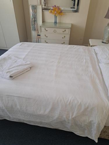 a white bed with a white dresser in a bedroom at Townhouse London in Seven Kings