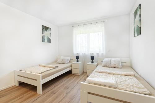 two beds in a room with white walls and wooden floors at Holiday Home Petar by Rent Istria in Buje
