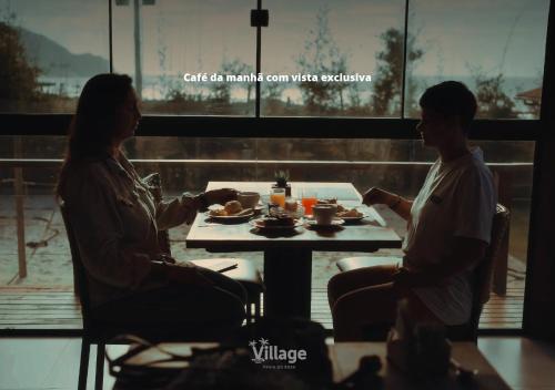 twee mensen aan een tafel eten bij Village Praia do Rosa in Praia do Rosa