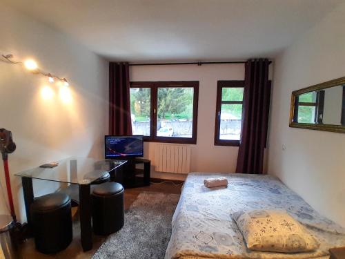 une chambre avec un lit, un bureau et une fenêtre dans l'établissement Y'Hôtes - Studio Evasion près des pistes, à Saint-Jeoire