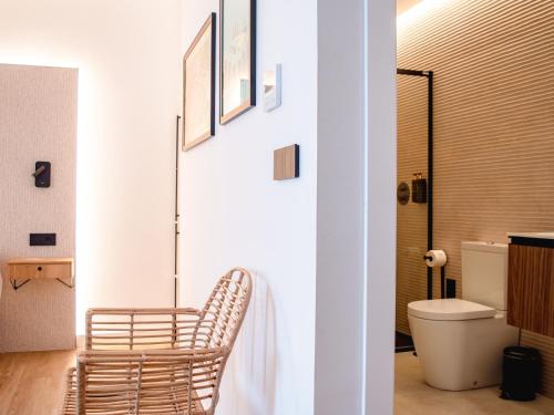 a bathroom with a rattan chair next to a toilet at Demetrio By Alma Suites in Valencia