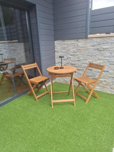 a table and two chairs on a patio with grass at loveroom avec spa privatif in Miniac-Morvan