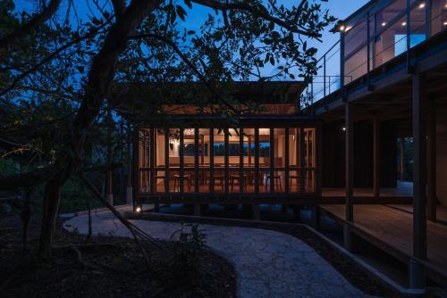 a modern house with a large deck at night at Bridgebuilders Tourist Home in Nanjo