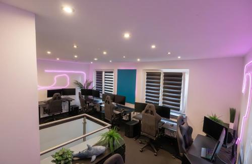an office with purple walls and desks and computers at World of Esport in Bayreuth