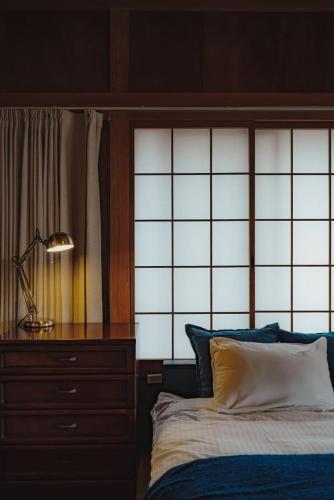 a bedroom with a bed and a dresser and a lamp at Unique City Pop Retreat 5 star Location, Game Room in Fujiyoshida