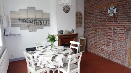 a dining room with a table and a brick wall at Gîte My Cottage Baie de Somme avec sauna in Cayeux-sur-Mer