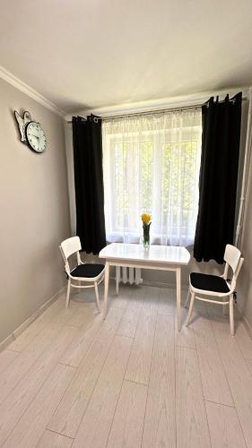 a living room with a table and two chairs and a window at Parkside Apartment Odesa in Odesa