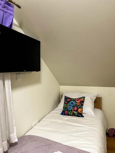 a small bed with a pillow and a flat screen tv at Lawendowa Willa in Kaczki Średnie