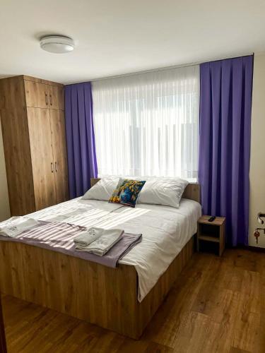 a bedroom with a large bed with purple curtains at Lawendowa Willa in Kaczki Średnie
