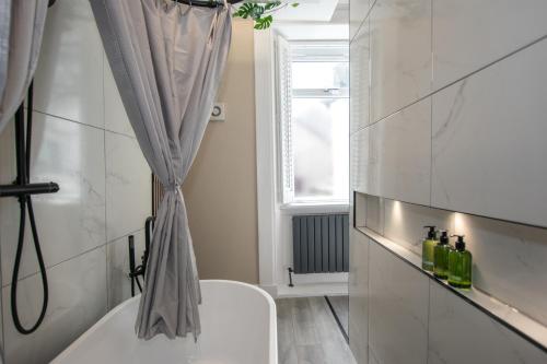 a bathroom with a tub and a toilet and a window at The White House near Edinburgh in Bathgate
