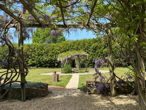 a garden with a pergola and purple flowers at The Old Pool House, Stylish Large Studio in Private Country Estate with Air Con in Bradford on Avon