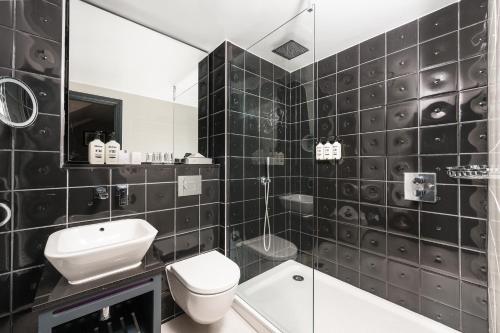 a black and white bathroom with a toilet and a sink at Hotel Indigo London - Kensington by IHG in London