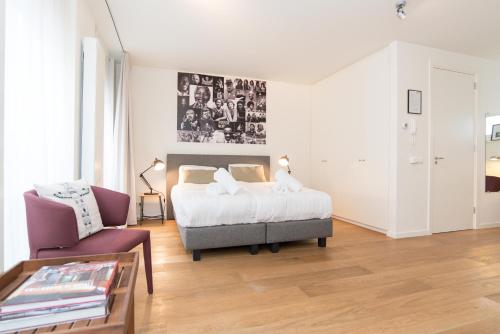 een slaapkamer met een bed en een stoel bij Apartments Grote Bickersstraat in Amsterdam