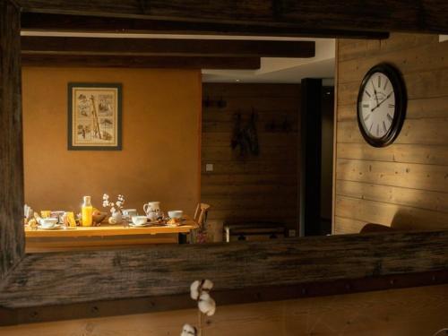 une pièce avec une table et une horloge au mur dans l'établissement Appartement 4 pièces pour 8/9 personnes, exposé Sud, au centre de Valloire, proche télécabine et loisirs - FR-1-263-216, à Valloire