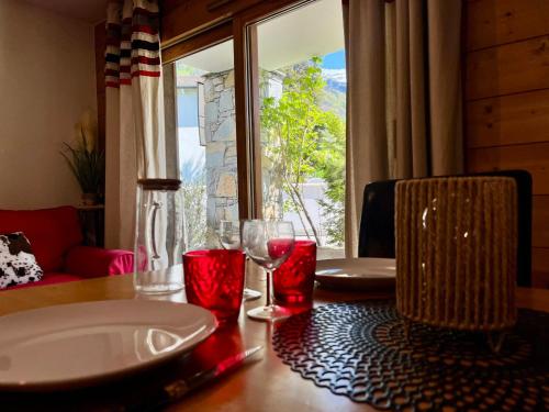 une table avec deux verres sur une table avec une fenêtre dans l'établissement Superbe appartement 48m² avec terrasse, centre village, parking, proche ski-bus, non-fumeur - FR-1-624-46, à Samoëns
