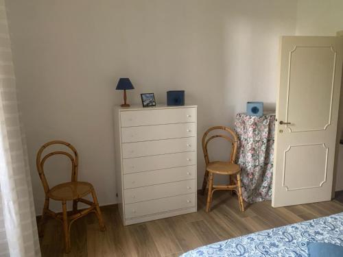 a bedroom with a white dresser and two chairs at Casa Maria Saturnia in Saturnia