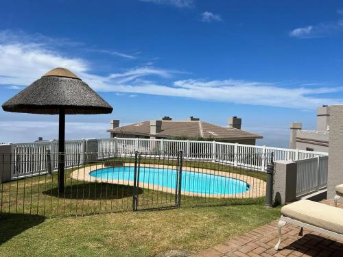 a fence around a swimming pool with an umbrella at 3 Bedroom Villa in Pinnacle Point Estate in Mossel Bay