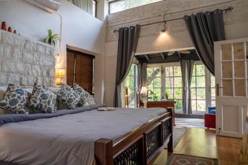 a bedroom with a large bed and large windows at The Owls Nest Farm in Dharmsāla
