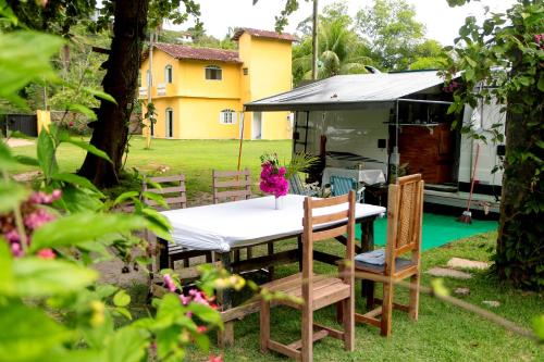 a table and chairs in a yard with a house at Vila Iriri - Pousada e Camping in Anchieta