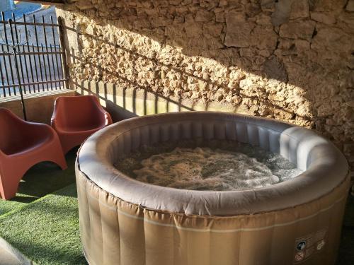 a hot tub in front of a wall with two chairs at Gîte de la Sablonnière in Haut-Orbé