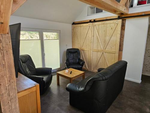 a living room with two black leather chairs and a table at Cottage am Michelsberg in Bad Münstereifel