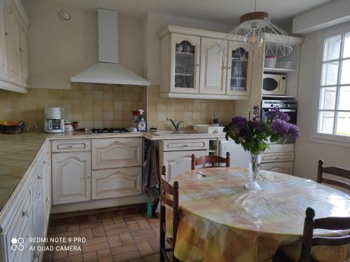 une cuisine avec une table avec un vase de fleurs dessus dans l'établissement les lilas, à Paimpol