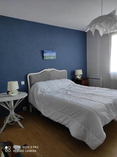 une chambre avec un grand lit avec un mur bleu dans l'établissement les lilas, à Paimpol