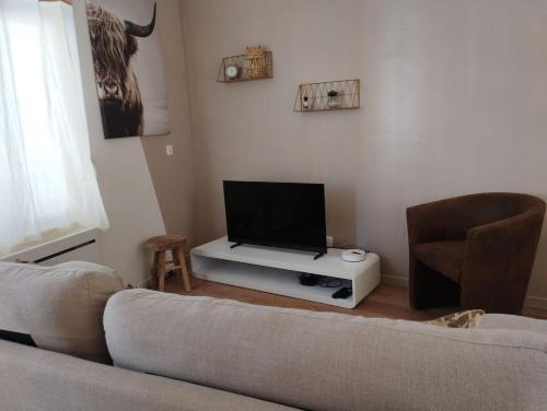 a living room with a couch and a flat screen tv at Petite maison de ville dans un quartier calme in Bourbourg