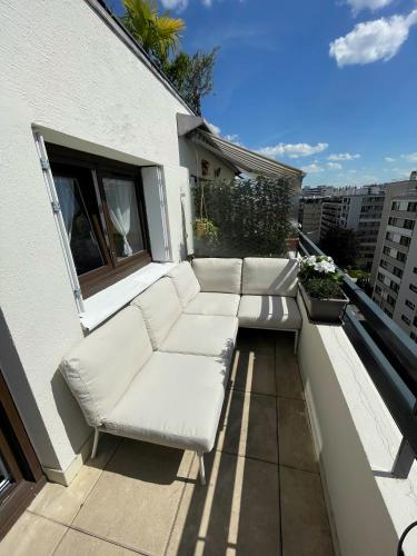 un ensemble de canapés blancs assis sur un balcon dans l'établissement Home F8 - Terrace Paris's view, Eiffel Tower area, à Paris