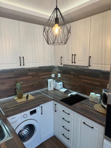 a kitchen with white cabinets and a washing machine at ORA SeaView in Balchik