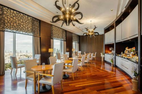 a dining room with tables and chairs and windows at Gulf Hotel Bahrain Convention and SPA in Manama