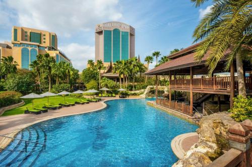 a pool at a resort with palm trees and buildings at Gulf Hotel Bahrain Convention and SPA in Manama