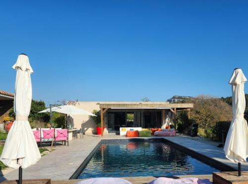 une piscine avec deux parasols et une maison dans l'établissement Piscine chauffée dans les vignes, à Roquefort-la-Bédoule