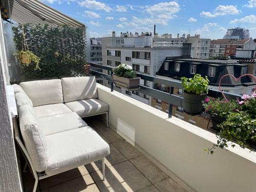 Elle dispose d'un balcon avec un canapé et des plantes. dans l'établissement Home F8 - Terrace Paris's view, Eiffel Tower area, à Paris