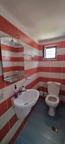 a red and white bathroom with a toilet and a sink at 2 Palmat Hotel in Ksamil
