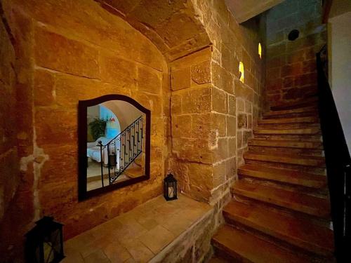 a staircase in a stone building with a mirror at 300 years old Maisonette in Beautiful Stairs in Valletta