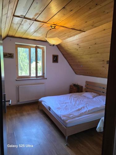 a bedroom with a bed and a wooden ceiling at Fabryka Snów in Ochotnica Górna