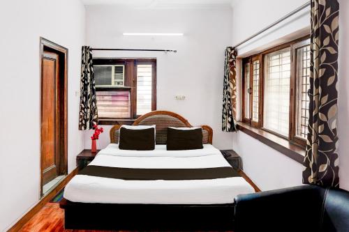 a bedroom with a large bed in a room with windows at Super Hotel O Krishna Nagar Chowk Near ONGC in Dehradun