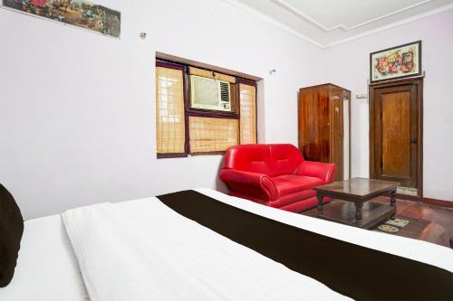 a bedroom with a bed and a red chair at Super Hotel O Krishna Nagar Chowk Near ONGC in Dehradun